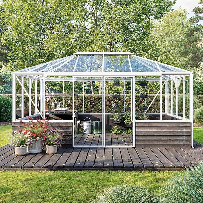 Fritstående pyramidedrivhus med glasoverdel og muret sokkel i haven