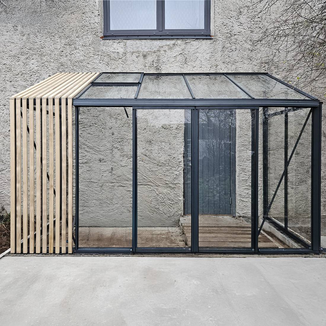 Vægmonteret drivhus med elegante glaspartier ved en dansk bolig